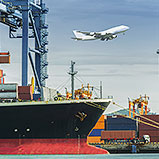 plane flying over container ship at port