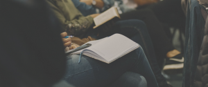casual audience members in row with notebooks in their laps