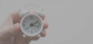 hand holding tiny white analog alarm clock