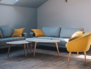 Small trendy room with two blue couches and a yellow chair